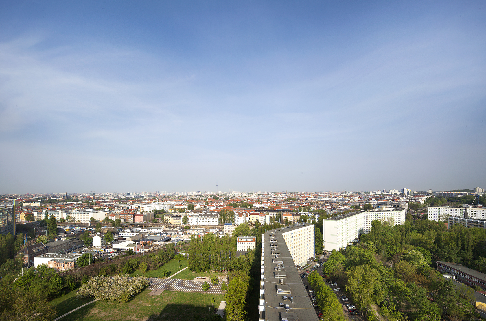 Das Bild zeigt viele Häuser, Straßen und Bäume. Es wurde von oben aufgenommen. Der Himmel ist blau.