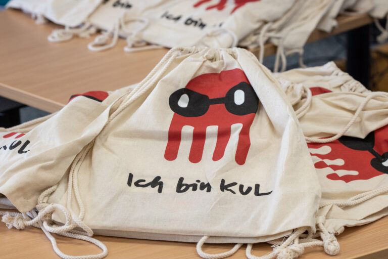 Abgebildet sind Jutebeutel bin den Aufdruck einer roten Krake und der Schrift 